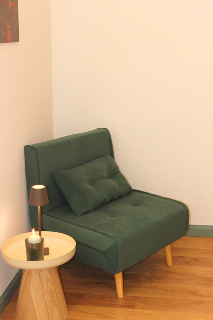 Green armchair and a side table with a lamp in a bedroom corner