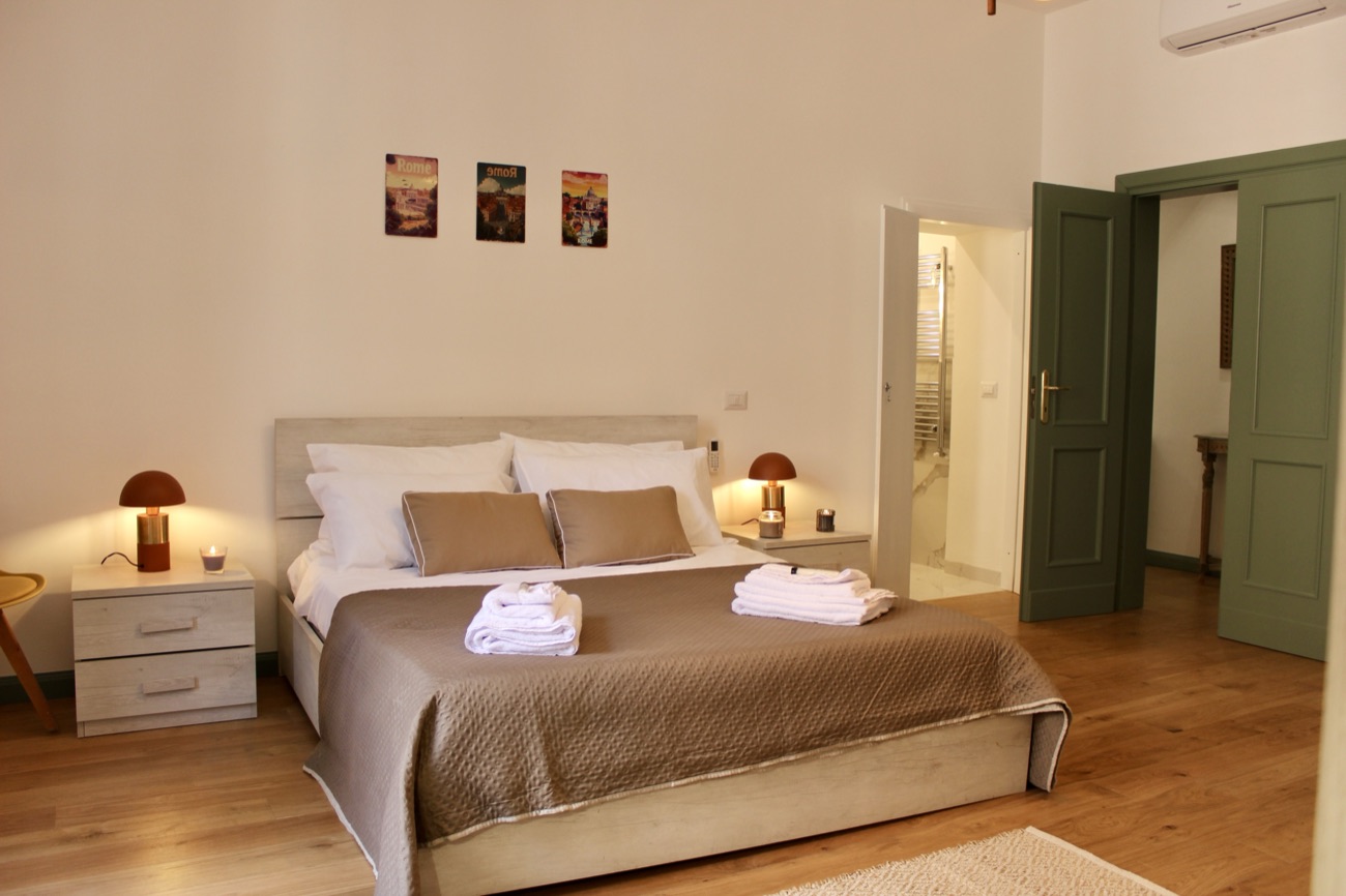 Double bed beside green double doors and the open bathroom door