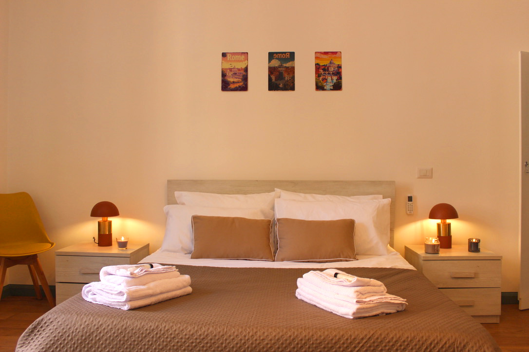 Double bed with folded towels and warm bedside lamps
