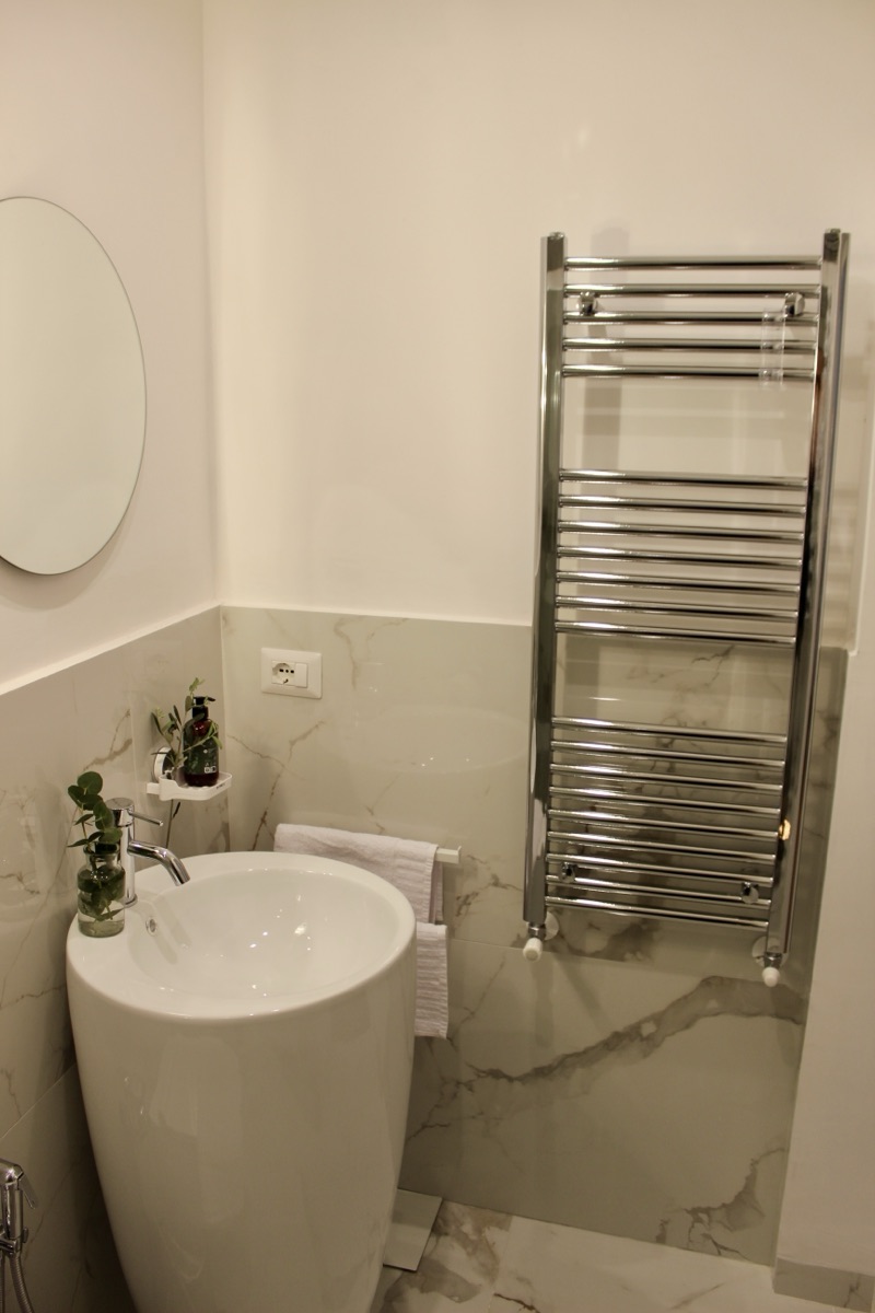 Marble bathroom with a pedestal sink and heated towel rail