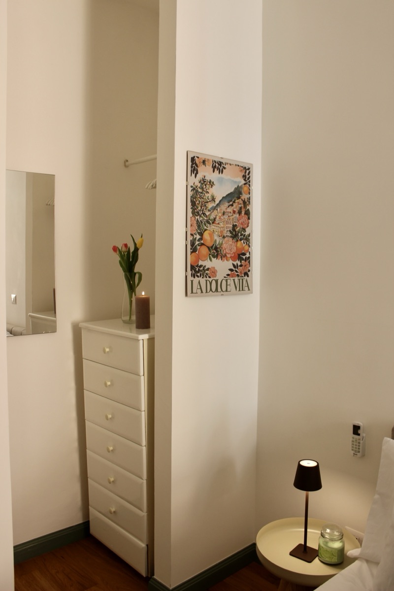 Chest of drawers, framed print and a bedside lamp in a bedroom corner