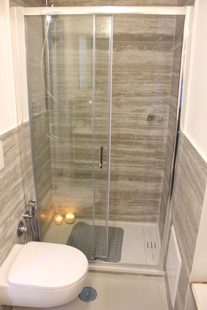 Glass shower with stone-effect tiles and candles