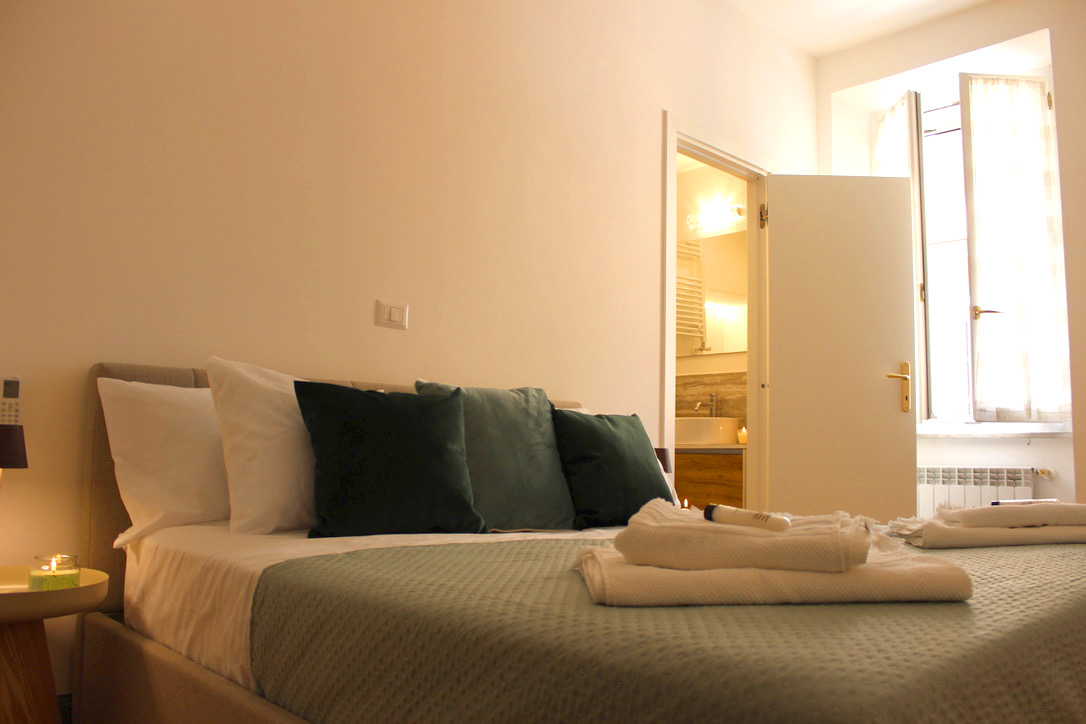 Bedroom with green cushions, an armchair and a door to the en-suite bathroom