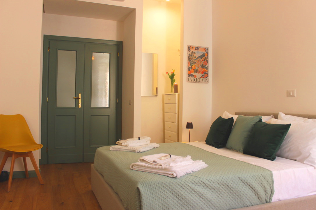 Ensuite 2: double bed with green cushions beside green double doors