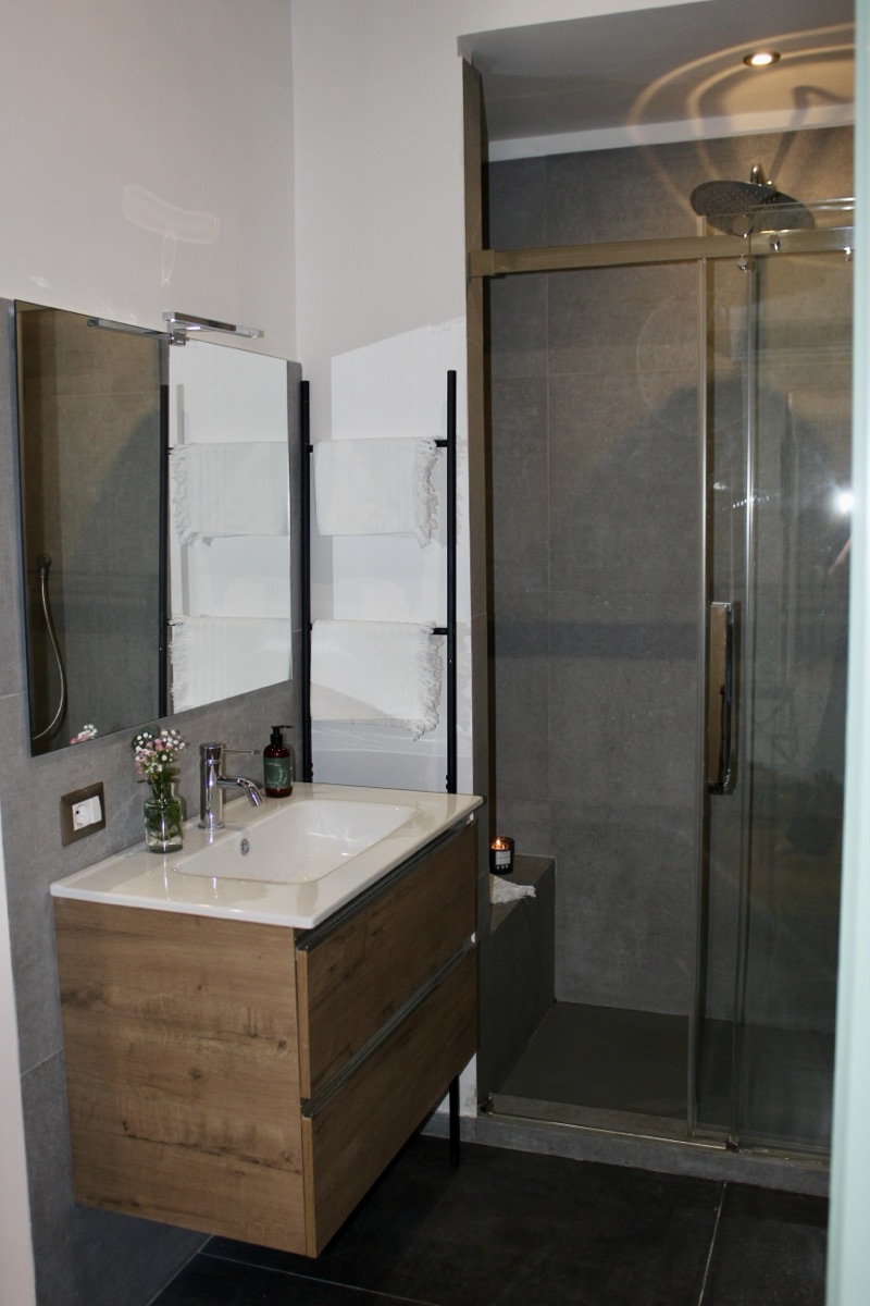 Walk-in shower and toilet in a gray-tiled bathroom