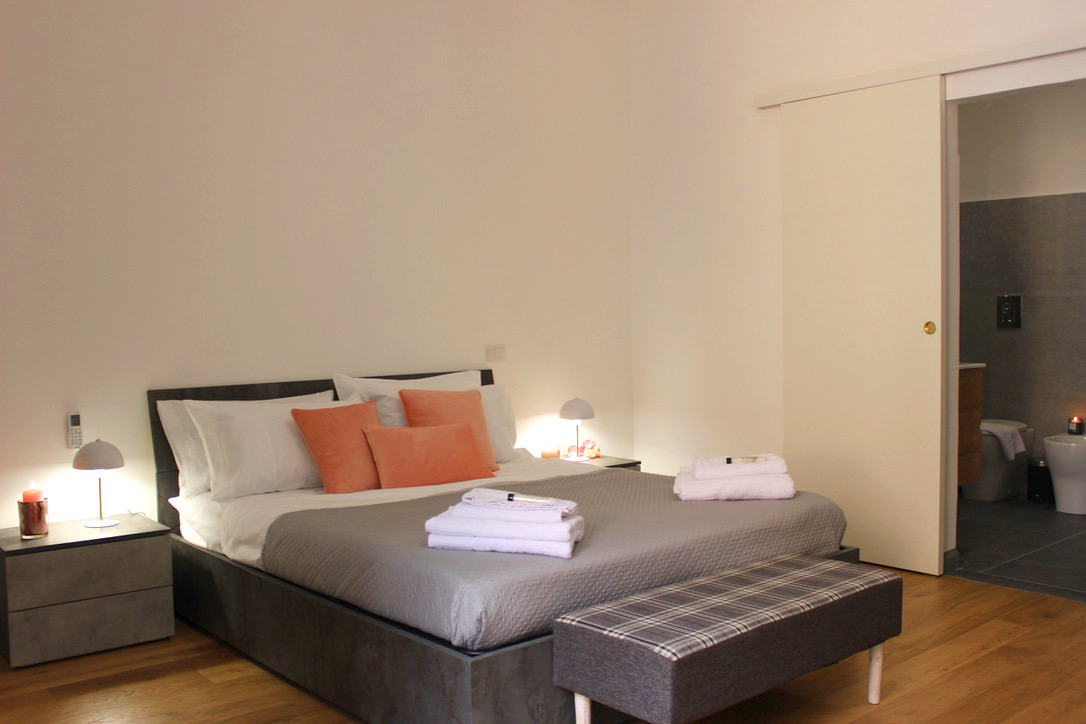 Ensuite 3: double bed with coral cushions and an upholstered bench