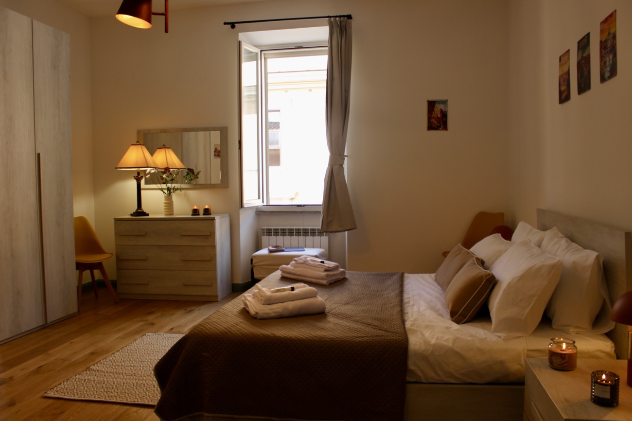 Bedroom in the evening with lamps lit and a window onto the street