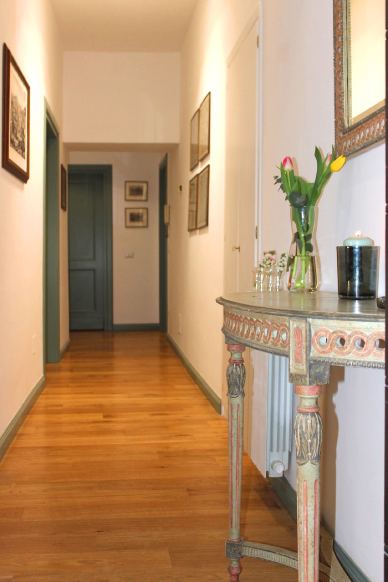 Hallway with wooden floors, framed prints and an antique console table