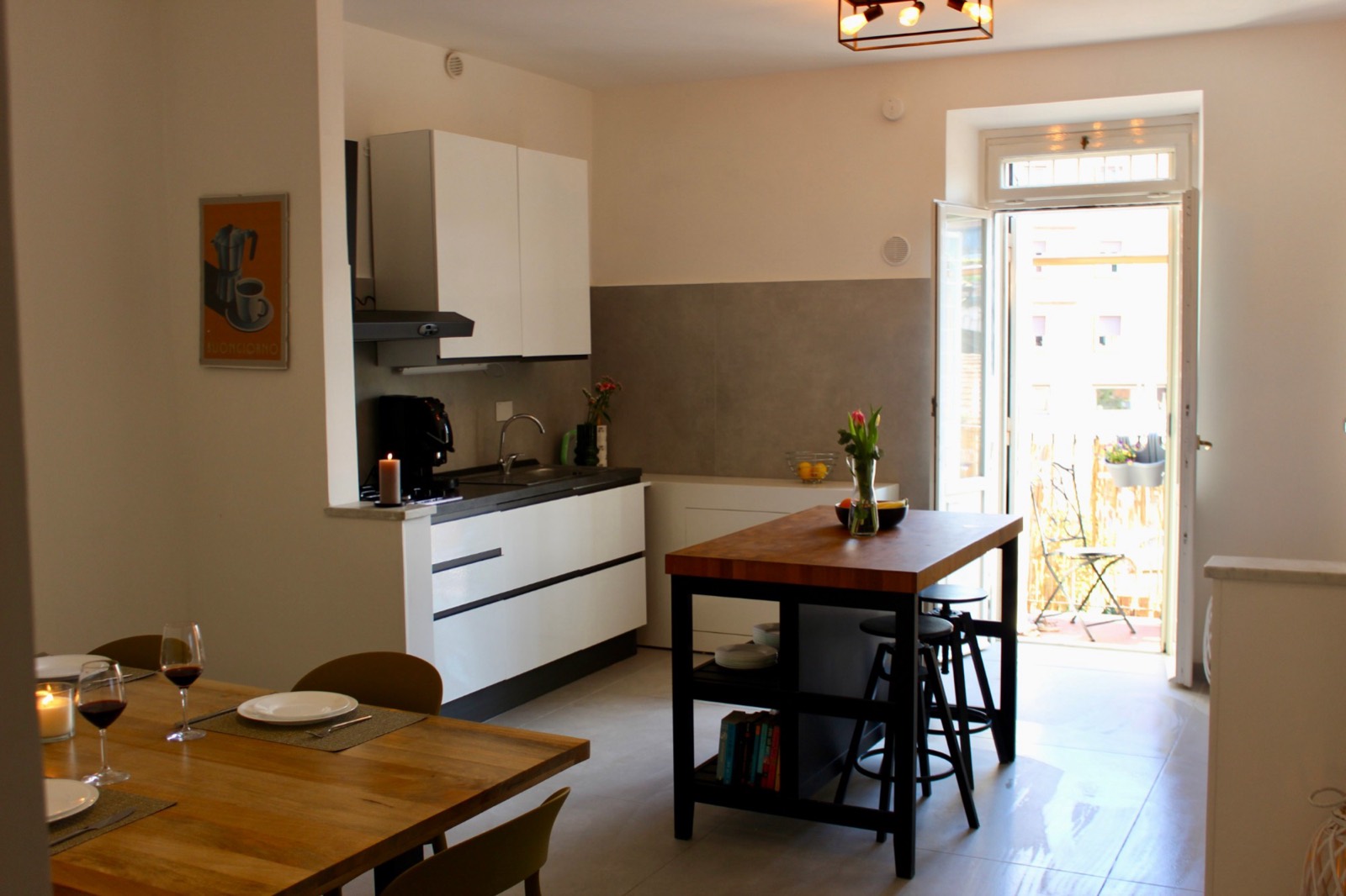 Open kitchen with a wooden island, dining table and doors to the balcony